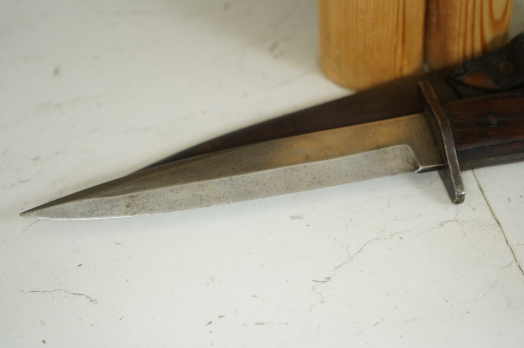 A First World War German Fighting Knife, with two piece wooden grip and steel cross guard, in original steel scabbard with leather belt loop mount, single edged blade with makers mark to one side; Gottlieb Hammesfahr, So